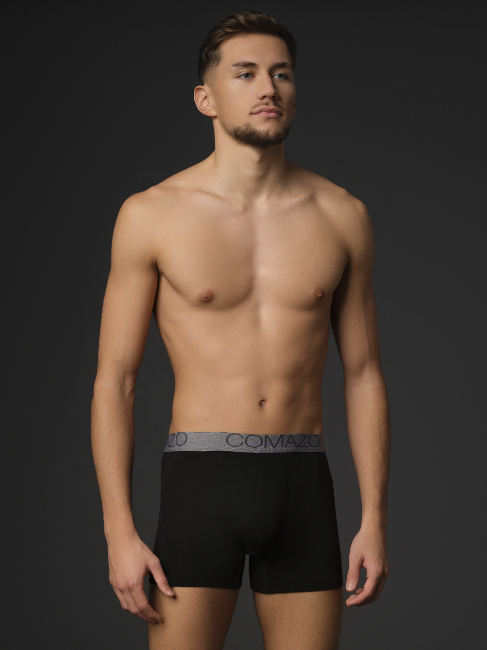 Comazo men's trunks made of merino wool in the color black. Front view 3: Man wearing merino wool trunks from Comazo in the color black with lettering on the waistband.