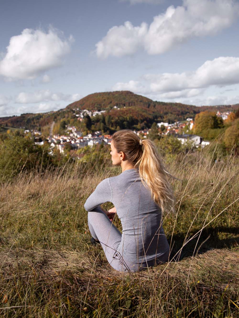 Comazo Unisex Functional Shirt "warm extra" Long Sleeve in Grey Mélange Back View Sitting: Woman wearing Unisex Functional Shirt "warm extra" Long Sleeve by Comazo in Grey Mélange