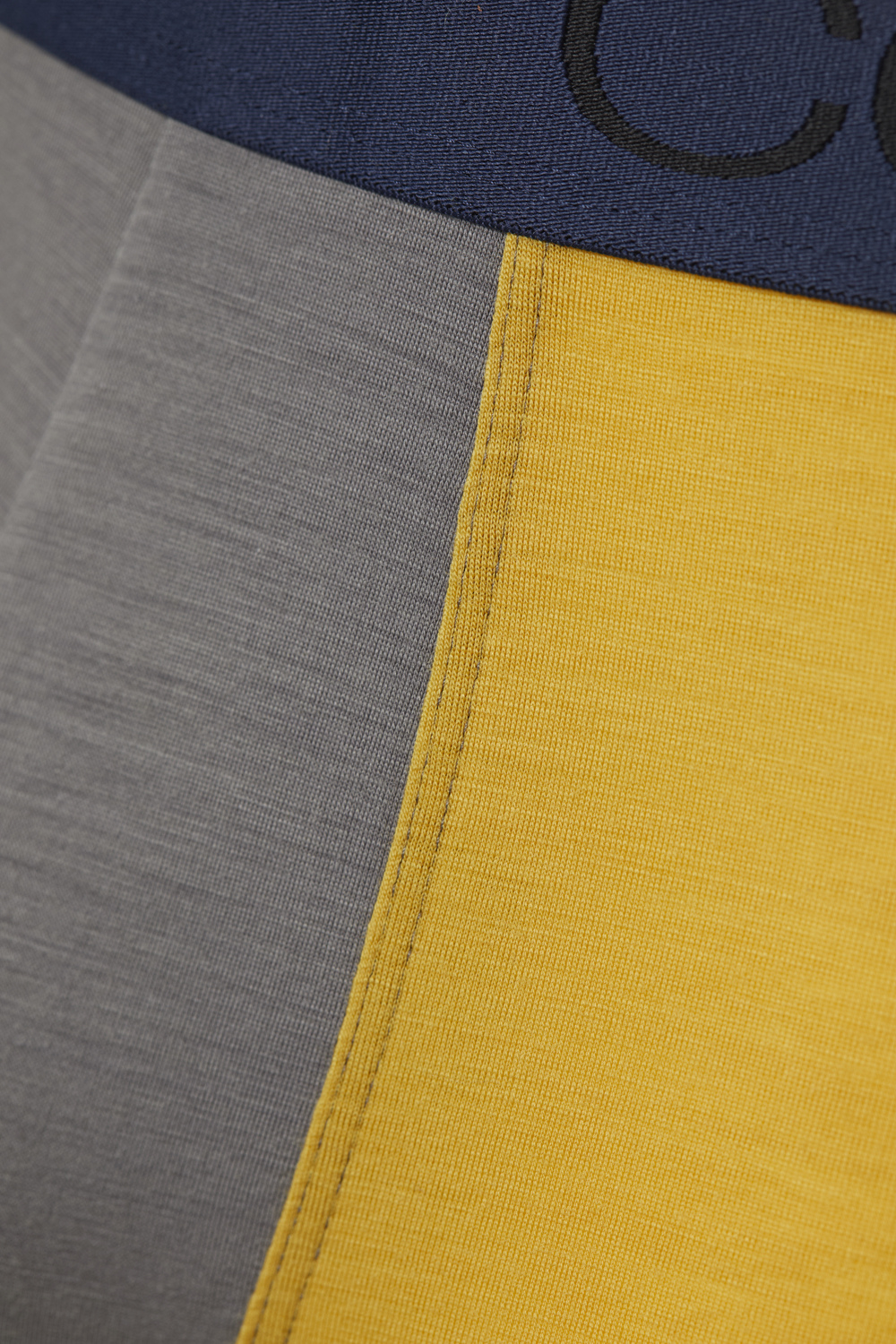 Comazo men's trunks made of merino wool in the color Steelgrey/Mustard. Detail image of the merino wool trunks from Comazo in the color Steelgrey/Mustard with lettering on the waistband.