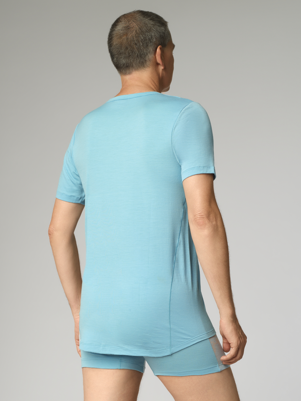 Comazo Herren Shirt kurzarm aus Merinowolle Farbe Seablue/Ice Rückansicht: Mann trägt Shirt kurzarm aus Merinowolle von Comazo in der Farbe Seablue/Ice mit längerem Rückenteil und Rundhalsausschnitt