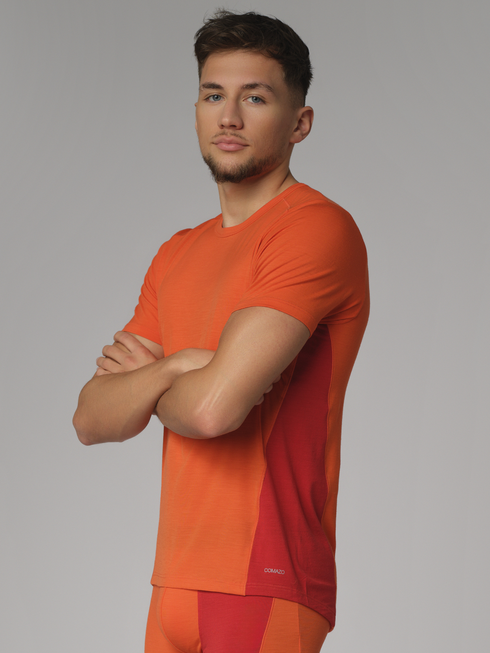 Comazo men's short-sleeve shirt made of merino wool, color orange/granite. Side view: Man wearing Comazo men's short-sleeve shirt made of merino wool, color orange/granite.