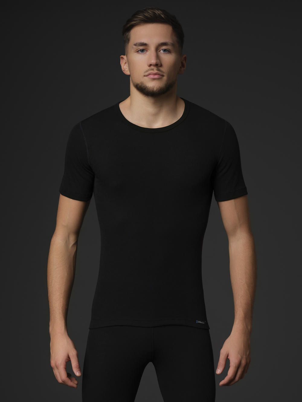 Comazo unisex short-sleeve functional shirt "warm extra", color black. Front view: Man wearing unisex short-sleeve functional shirt "warm extra" by Comazo in black, with a brushed inner lining for optimal heat retention, moisture management, and an extended back panel.