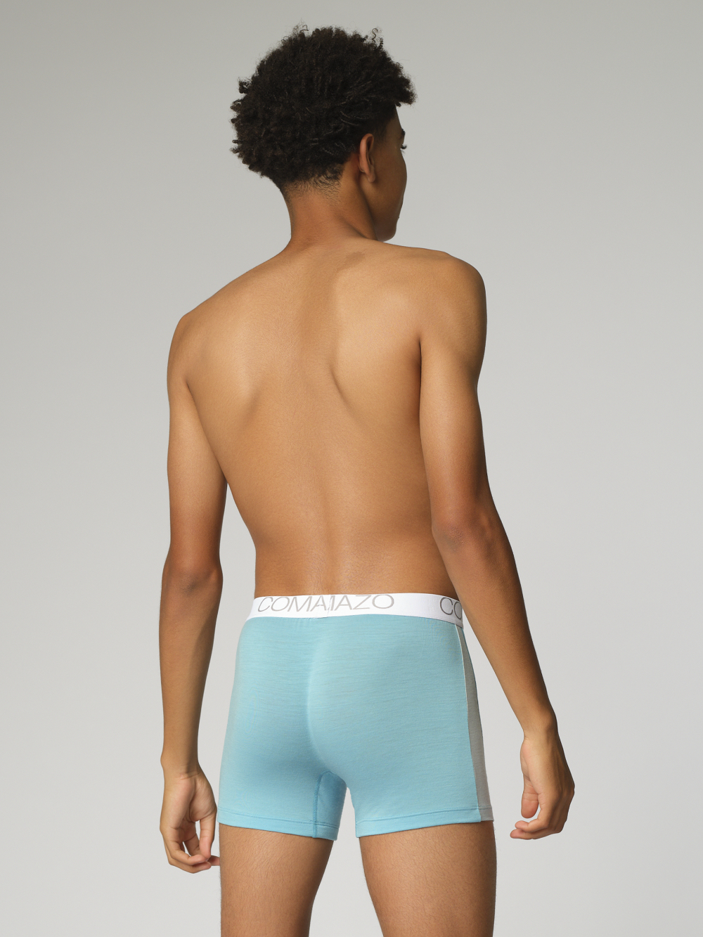 Comazo men's trunks made of merino wool in the color Seablue/Ice. Back view: Man wearing merino wool trunks from Comazo in the color Seablue/Ice with lettering on the waistband.