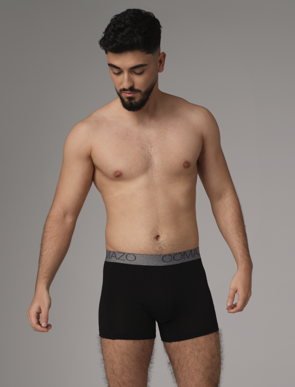 Comazo men's trunks made of merino wool in the color black. Front view 2: Man wearing merino wool trunks from Comazo in the color black with lettering on the waistband.