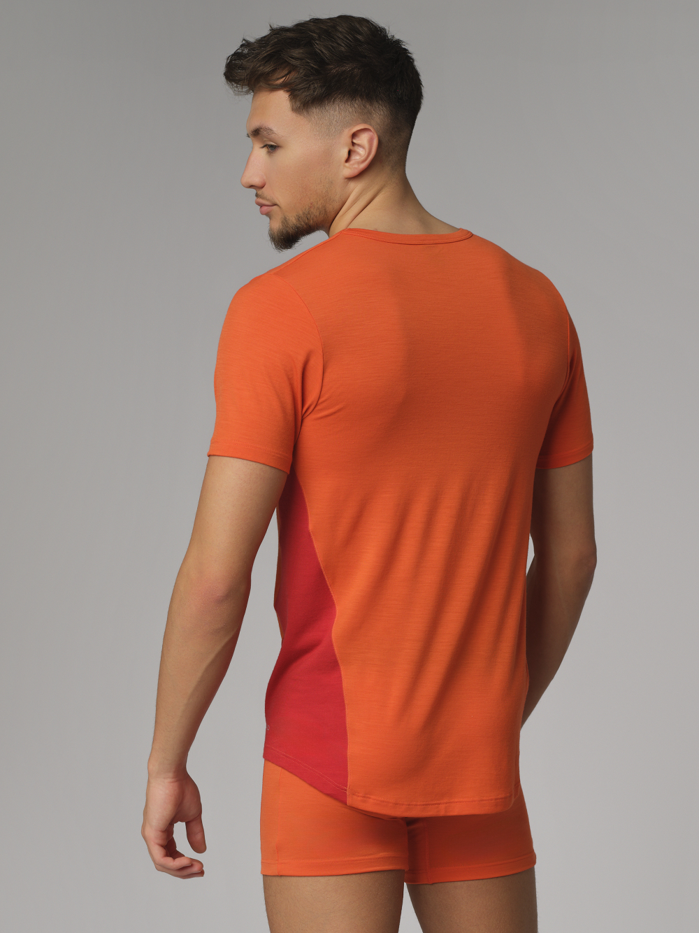 Comazo men's short-sleeve shirt made of merino wool, color orange/granite. Back view: Man wearing Comazo men's short-sleeve shirt made of merino wool, color orange/granite.