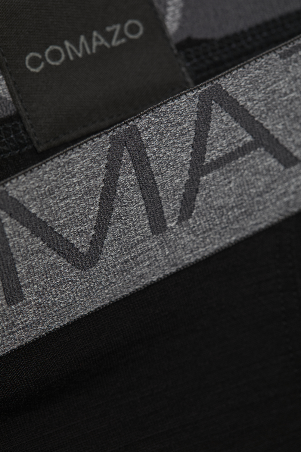 Comazo men's trunks made of merino wool in the color black. Detail image of the merino wool trunks from Comazo in the color black with lettering on the waistband.