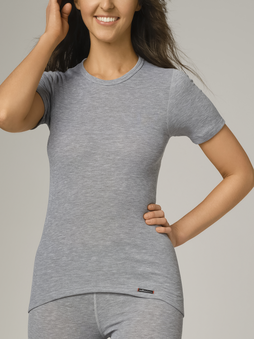 Comazo unisex short-sleeve functional shirt "warm extra", color gray melange. Front view: Women wearing unisex short-sleeve functional shirt "warm extra" by Comazo in gray melange, with a brushed inner lining for optimal heat retention, moisture management, and an extended back panel.