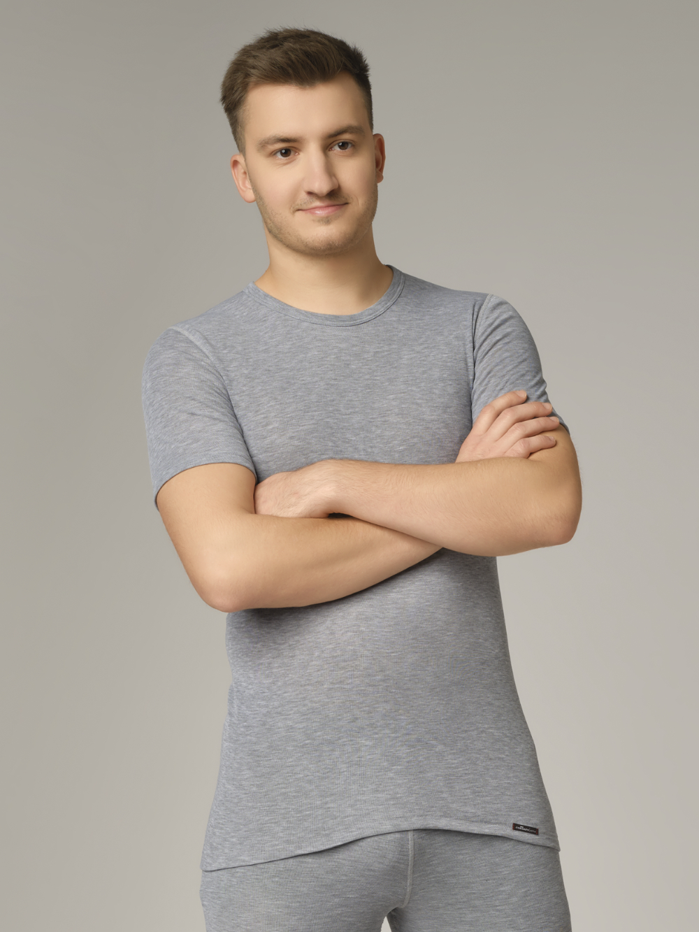 Comazo unisex short-sleeve functional shirt "warm extra", color gray melange. Front view: Man wearing unisex short-sleeve functional shirt "warm extra" by Comazo in gray melange, with a brushed inner lining for optimal heat retention, moisture management, and an extended back panel.