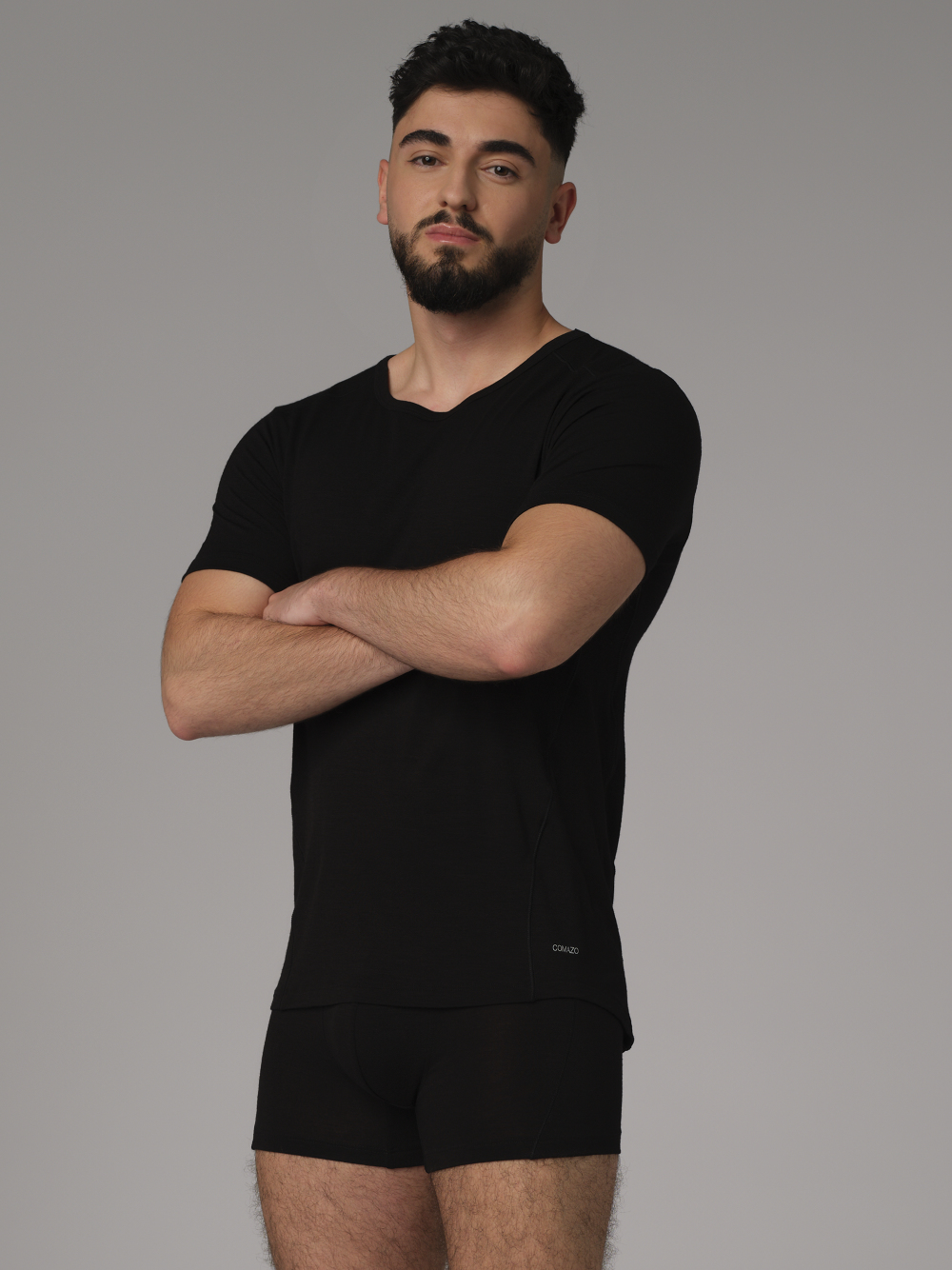 Comazo men's short-sleeve shirt made of merino wool, color black. Front view: Man wearing a short-sleeve shirt made of merino wool by Comazo in black color with extended back panel and crew neck.