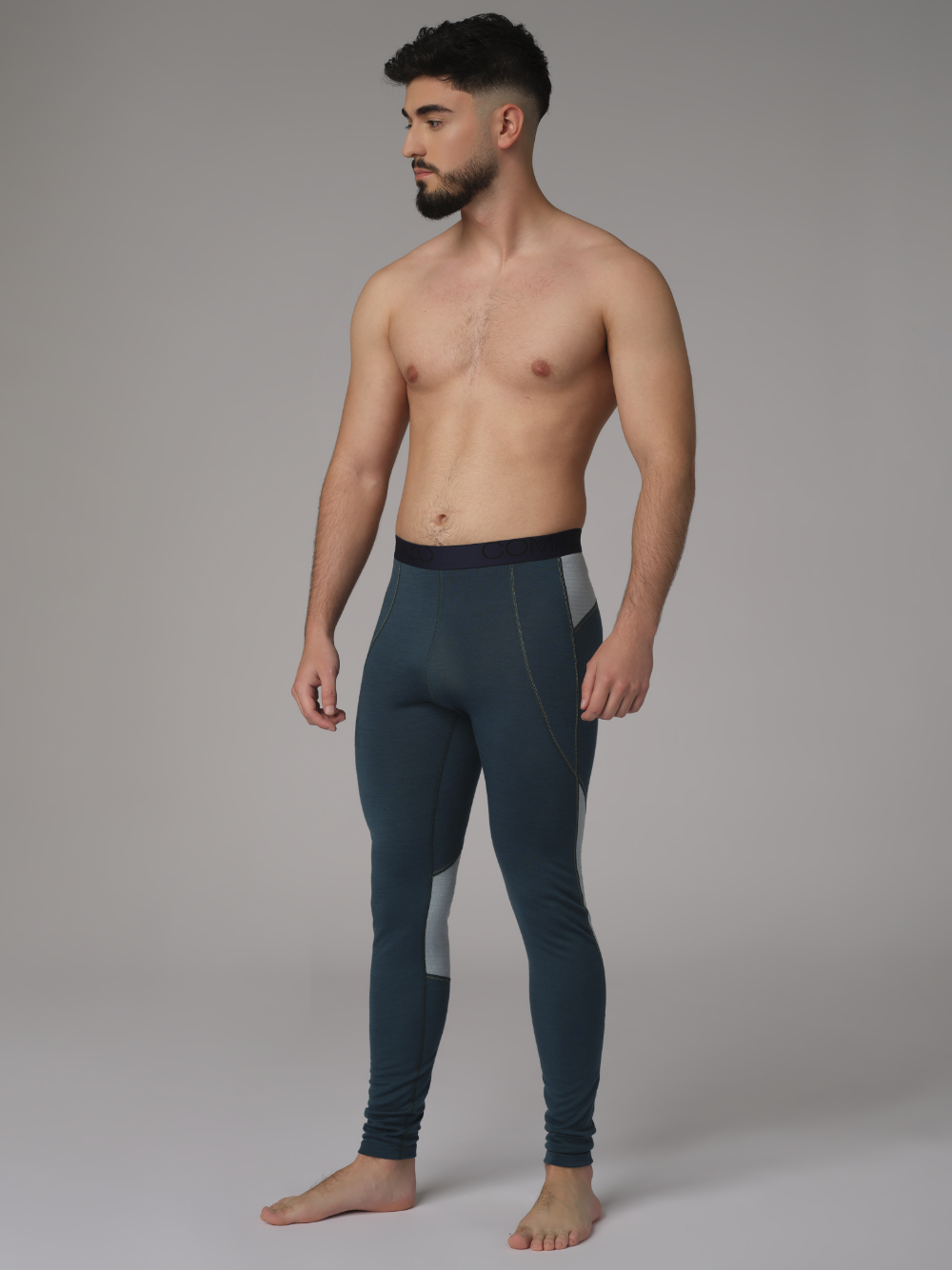Comazo men's long underpants made of merino wool, color emerald/light green. Front view: Man wearing long underpants made of 100% mulesing-free merino wool by Comazo in emerald/light green color with Comazo logo waistband.