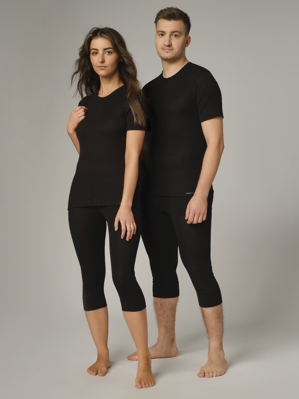 Comazo Unisex 3/4 Funktionshose "warm extra" Farbe Schwarz Vorderansicht: Eine Frau und ein Mann tragen Unisex 3/4 Funktionshose "warm extra" von Comazo in der Farbe Schwarz mit angerauter Innenseite zur optimalen Wärmespeicherung und schnelltrocknendem Funktionsmaterial dank sehr gutem Feuchtigkeitstransport