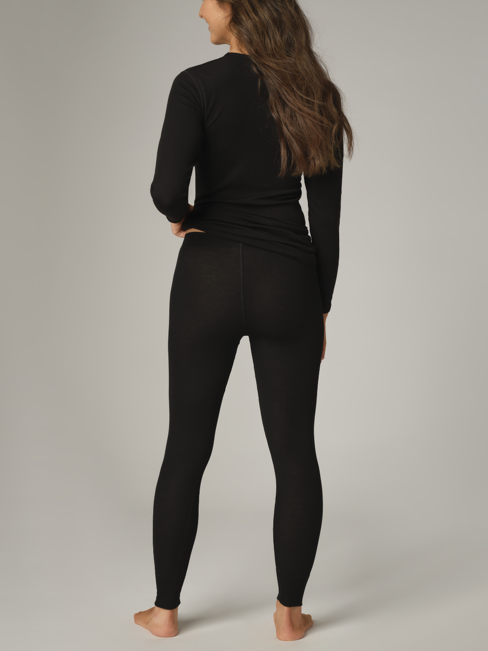 Comazo Unisex Funktionshose "warm extra" Farbe Schwarz Rückansicht: Frau trägt  Unisex Funktionshose "warm extra" lang von Comazo in der Farbe Schwarz mit angerauter Innenseite zur optimalen Wärmespeicherung und schnelltrocknendem Funktionsmaterial dank sehr gutem Feuchtigkeitstransport