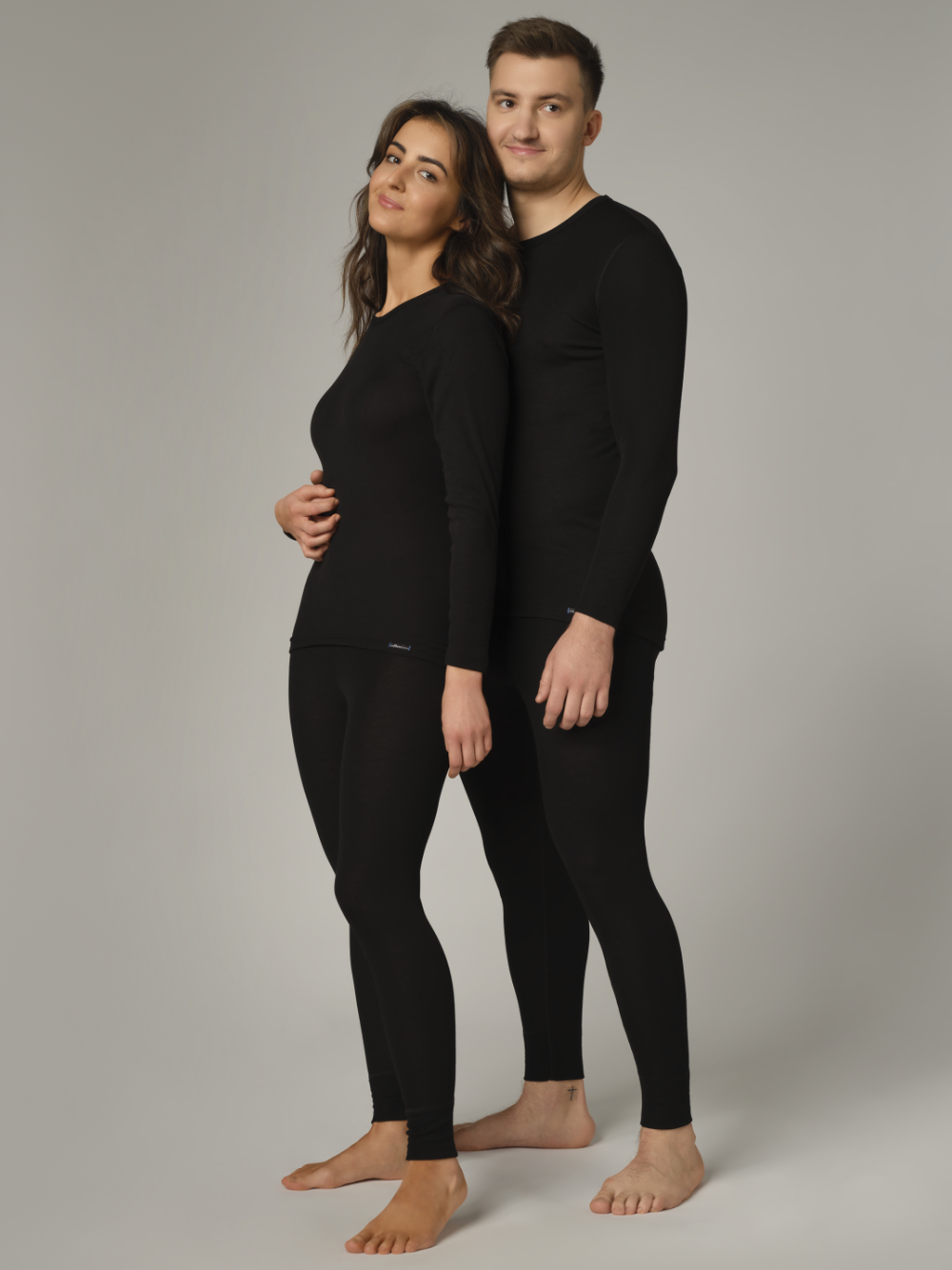 Comazo Unisex Funktionshose "warm extra" Farbe Schwarz Vorderansicht: Eine Frau und ein Mann tragen Unisex Funktionshose "warm extra" lang von Comazo in der Farbe Schwarz mit angerauter Innenseite zur optimalen Wärmespeicherung und schnelltrocknendem Funktionsmaterial dank sehr gutem Feuchtigkeitstransport