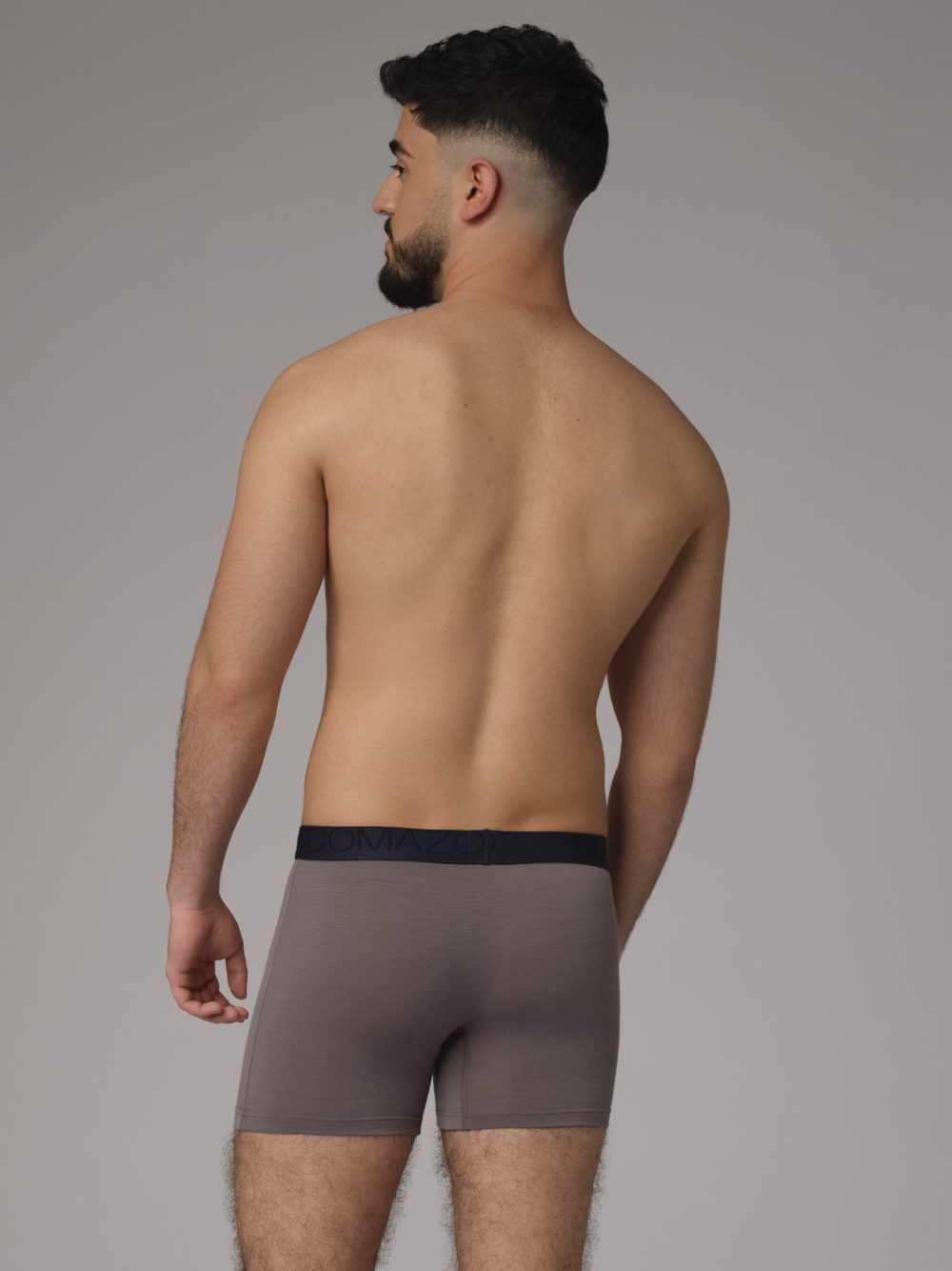 Comazo men's trunks made of merino wool in the color Steelgrey/Mustard. Back view: Man wearing merino wool trunks from Comazo in the color Steelgrey/Mustard with lettering on the waistband.