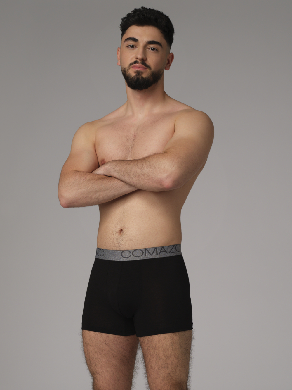 Comazo men's trunks made of merino wool in the color black. Front view : Man wearing merino wool trunks from Comazo in the color black with lettering on the waistband.