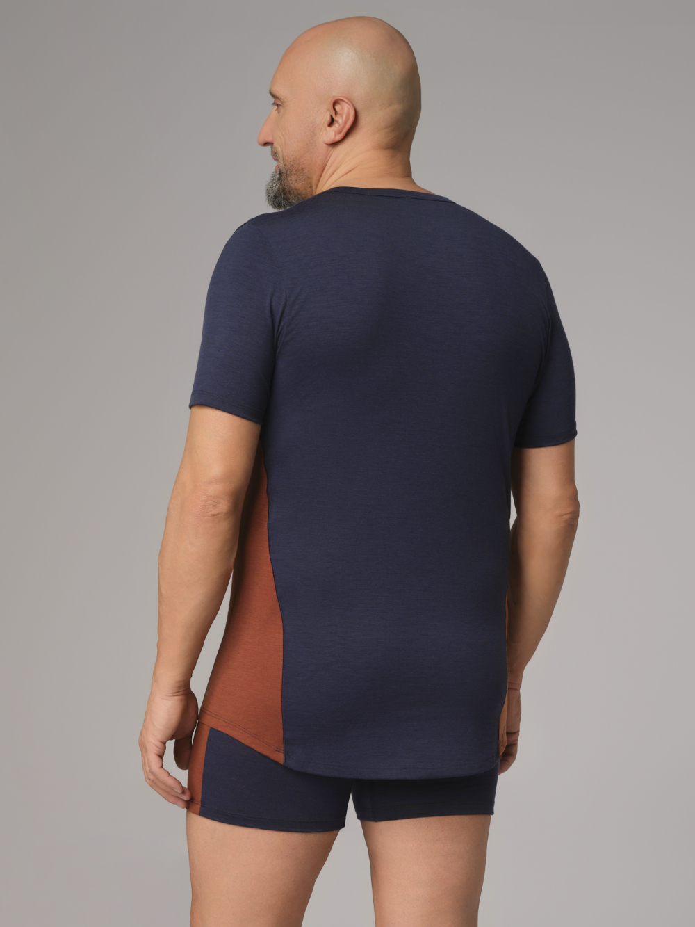 Comazo Herren Shirt kurzarm aus Merinowolle Farbe Navy/Schoko Rückansicht: Mann trägt Shirt kurzarm aus Merinowolle von Comazo in der Farbe Navy/Schoko mit längerem Rückenteil und Rundhalsausschnitt