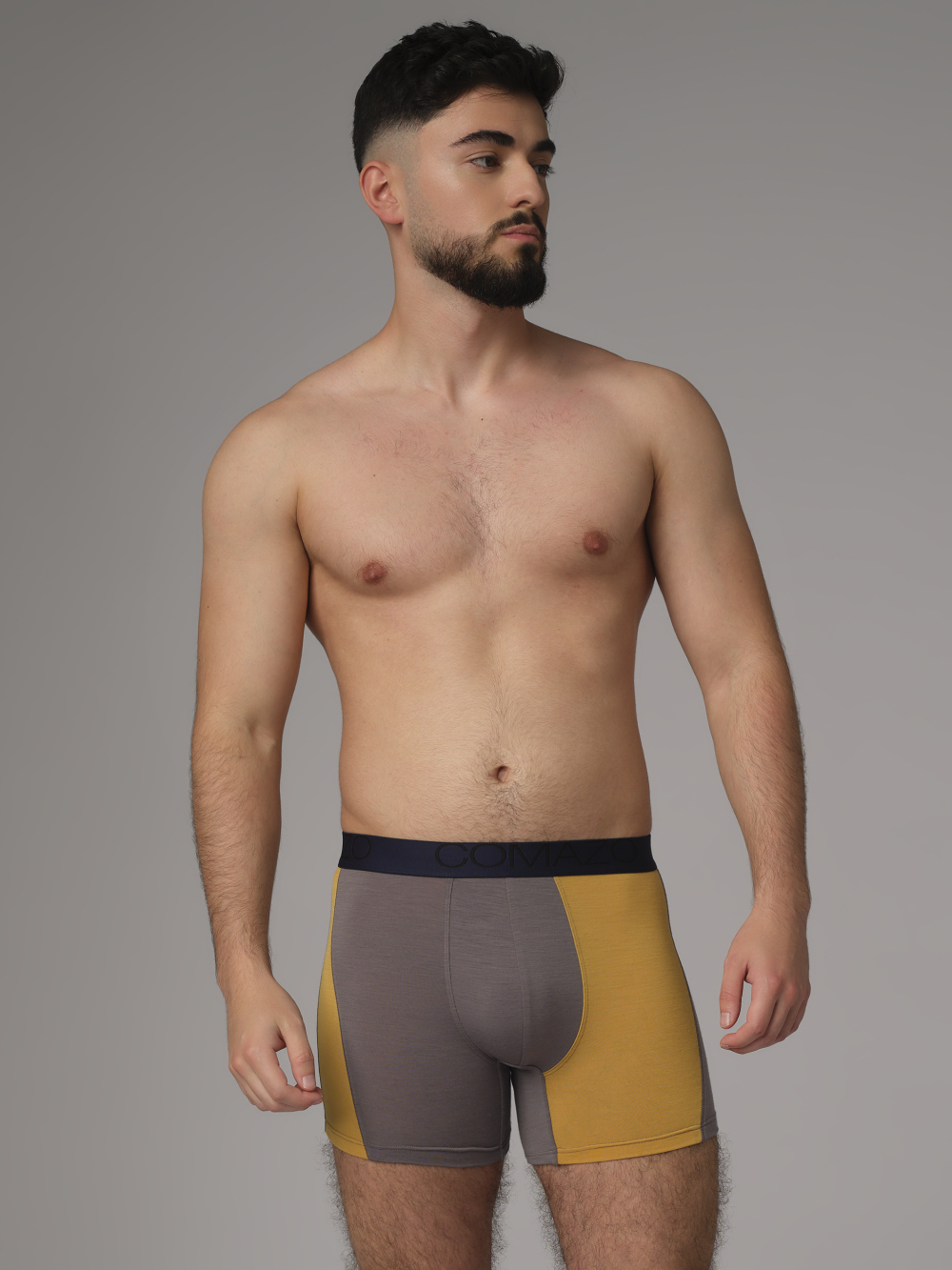 Comazo men's trunks made of merino wool in the color Steelgrey/Mustard. Front view: Man wearing merino wool trunks from Comazo in the color Steelgrey/Mustard with lettering on the waistband.