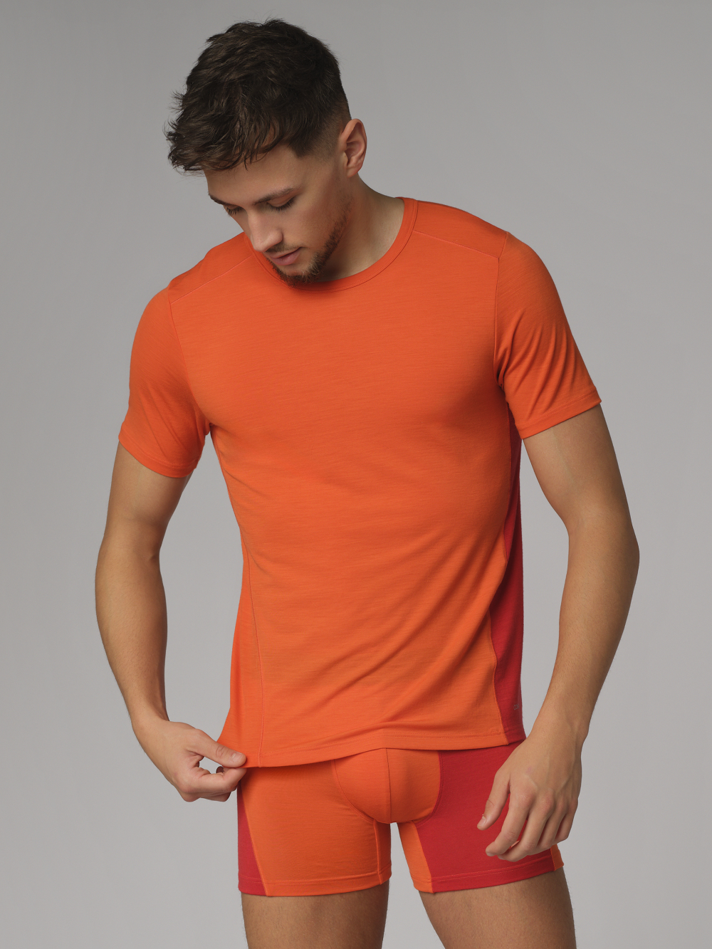 Comazo men's short-sleeve shirt made of merino wool, color orange/granite. Front view: Man wearing Comazo men's short-sleeve shirt made of merino wool, color orange/granite.